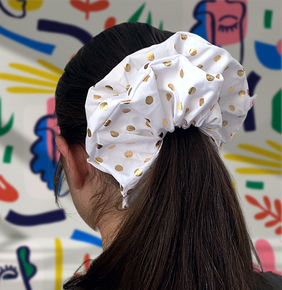 Back view of a modern woman showcasing ANASSTASIAN's white scrunchie with gold dots, adding a touch of contemporary elegance to her style.